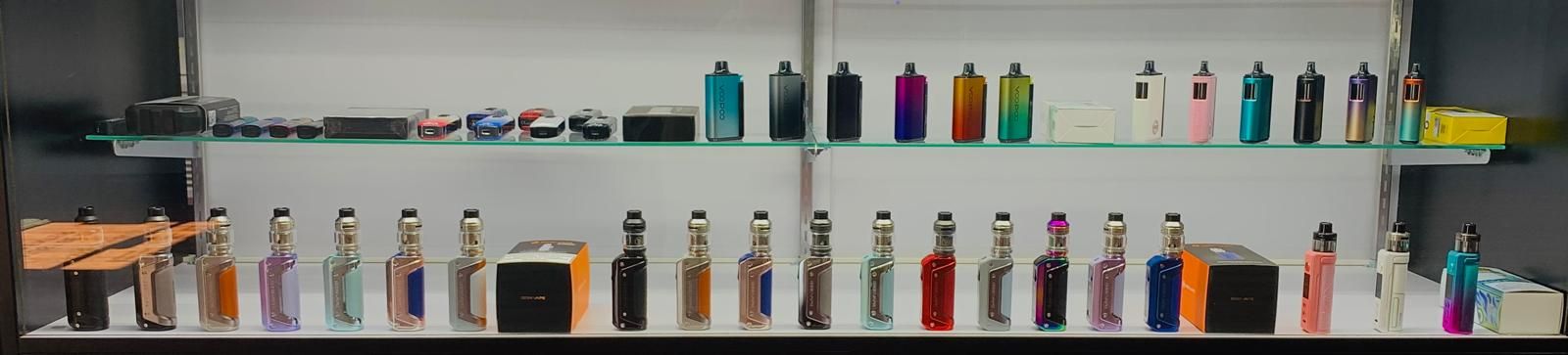 A retail display shelf stocked with various colorful vape pens and devices arranged in rows.