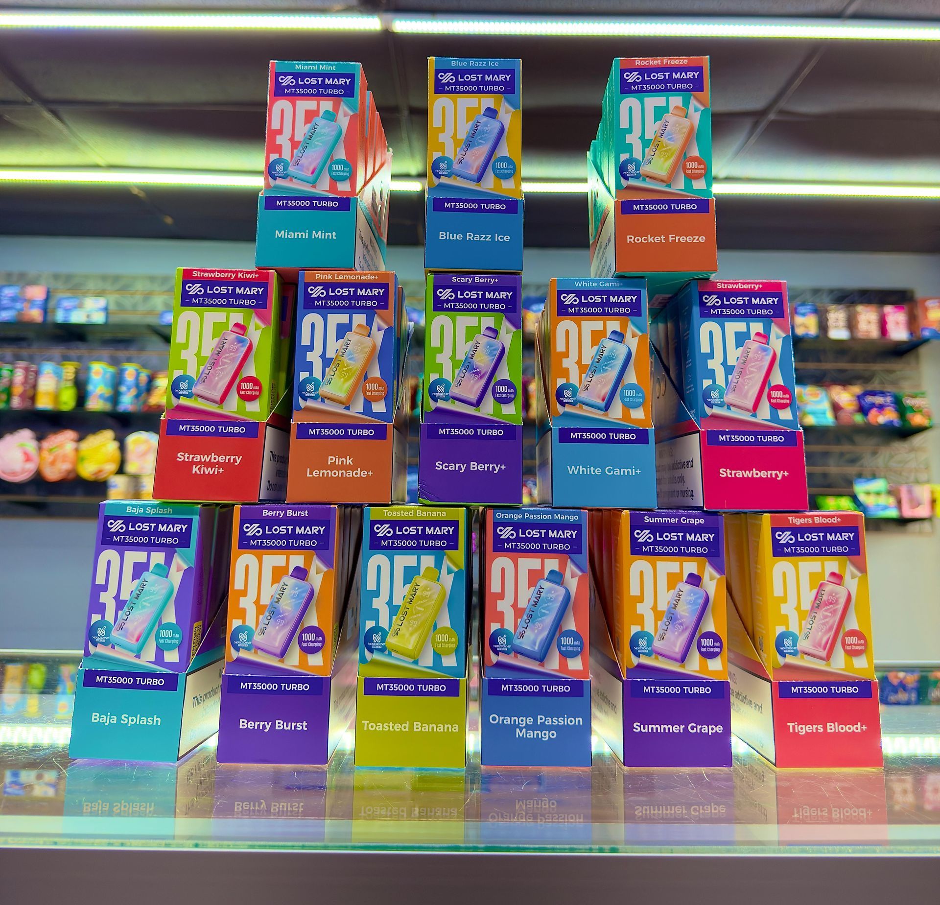 A pyramid display of colorful, individually packaged disposable vape products on a store counter.
