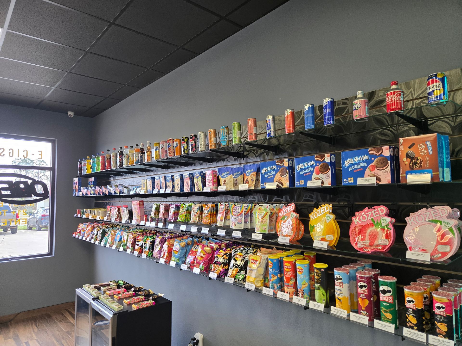 Shelves in a snack shop displaying a wide variety of colorful packaged snacks, boxes, and Pringles cans.