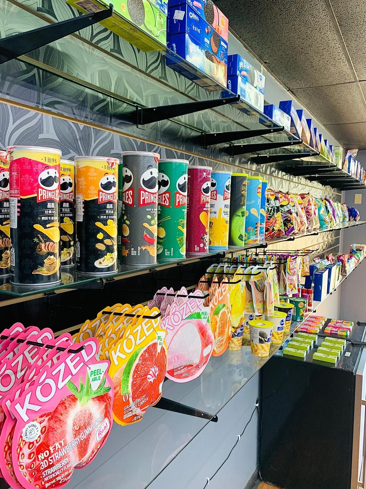 Rows of Pringles cans and various snack packages displayed on shelves in a retail store.