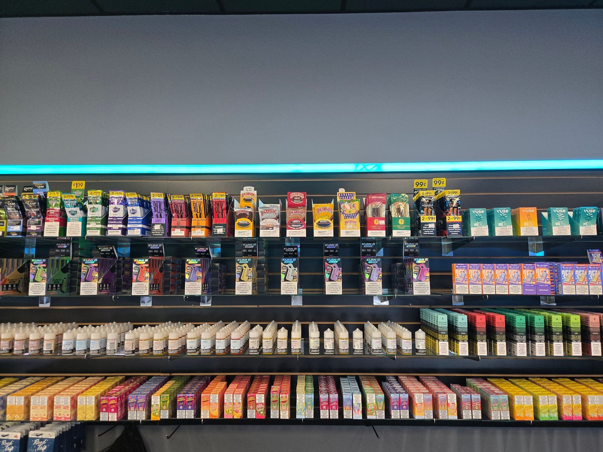 A retail shelf display filled with rows of colorful boxed vaping products and bottles of e-liquid.