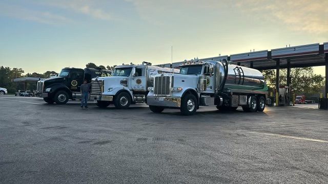 Three trucks are parked next to a gas station.