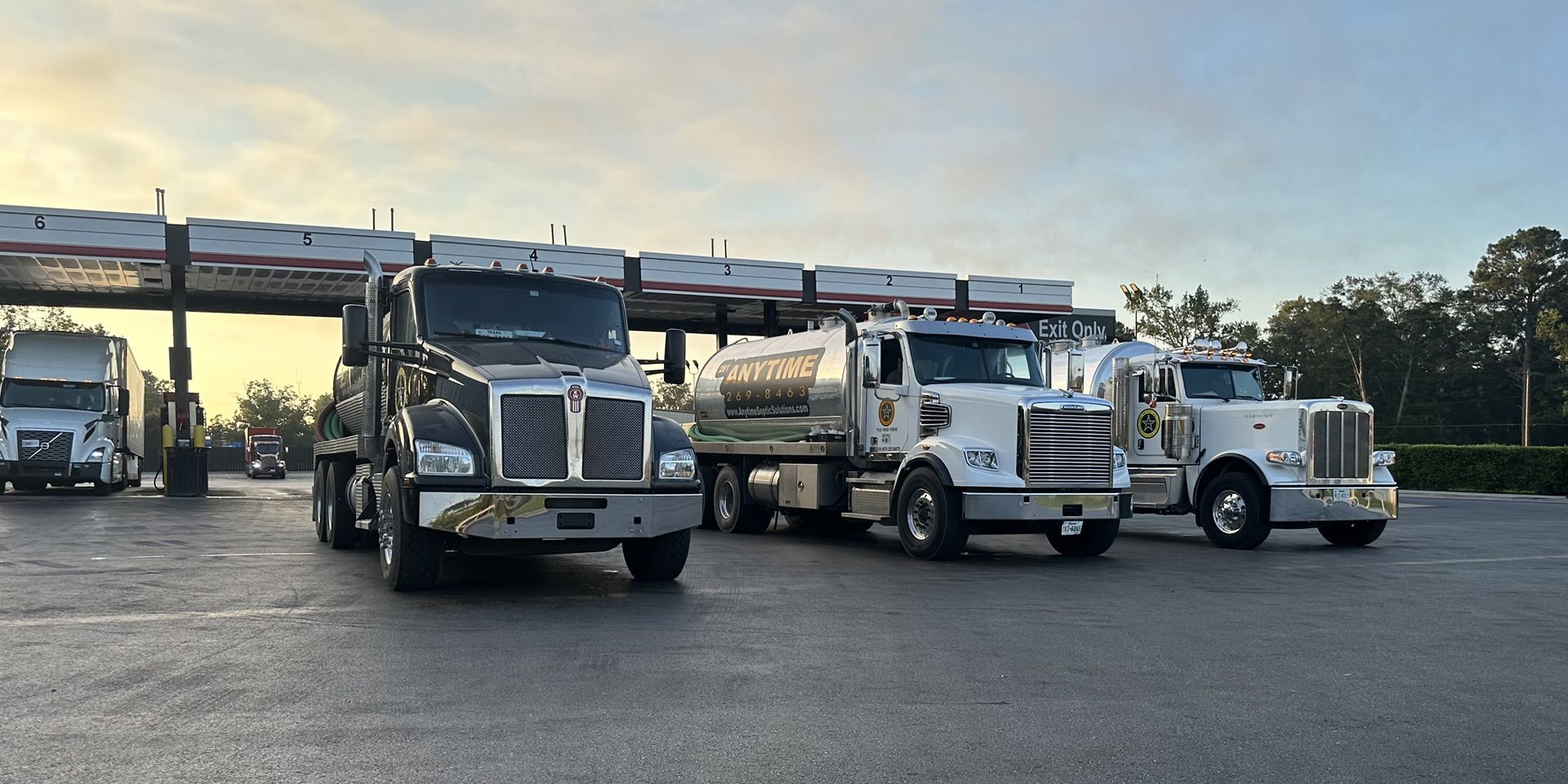 A row of septic trucks are parked in a parking lot