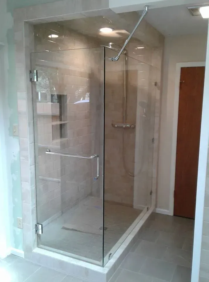 Glass shower enclosure with gray tile walls and floor, chrome fixtures.