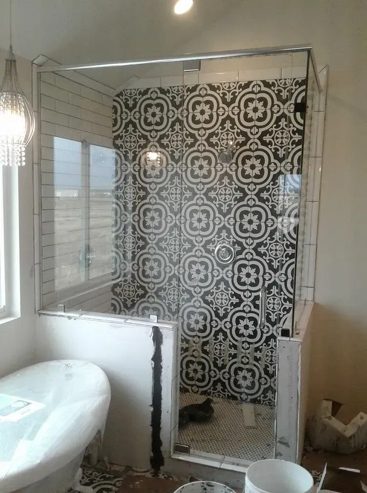 Bathroom shower with black and white patterned tile and glass doors.
