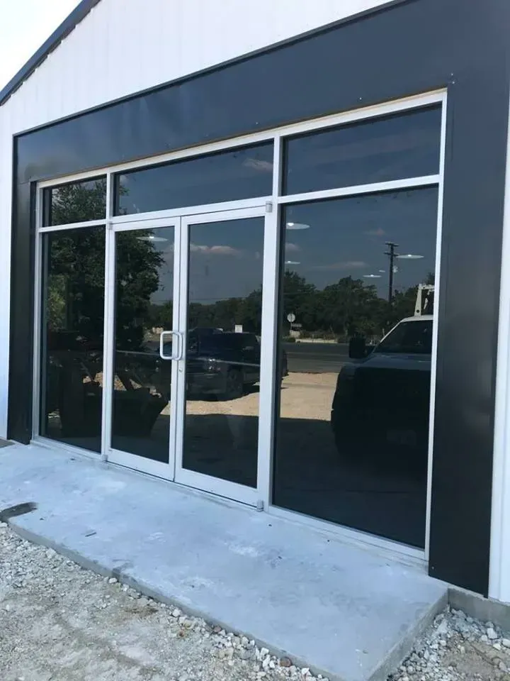 Glass doors and windows with tinted glass on a building with white and black exterior walls.
