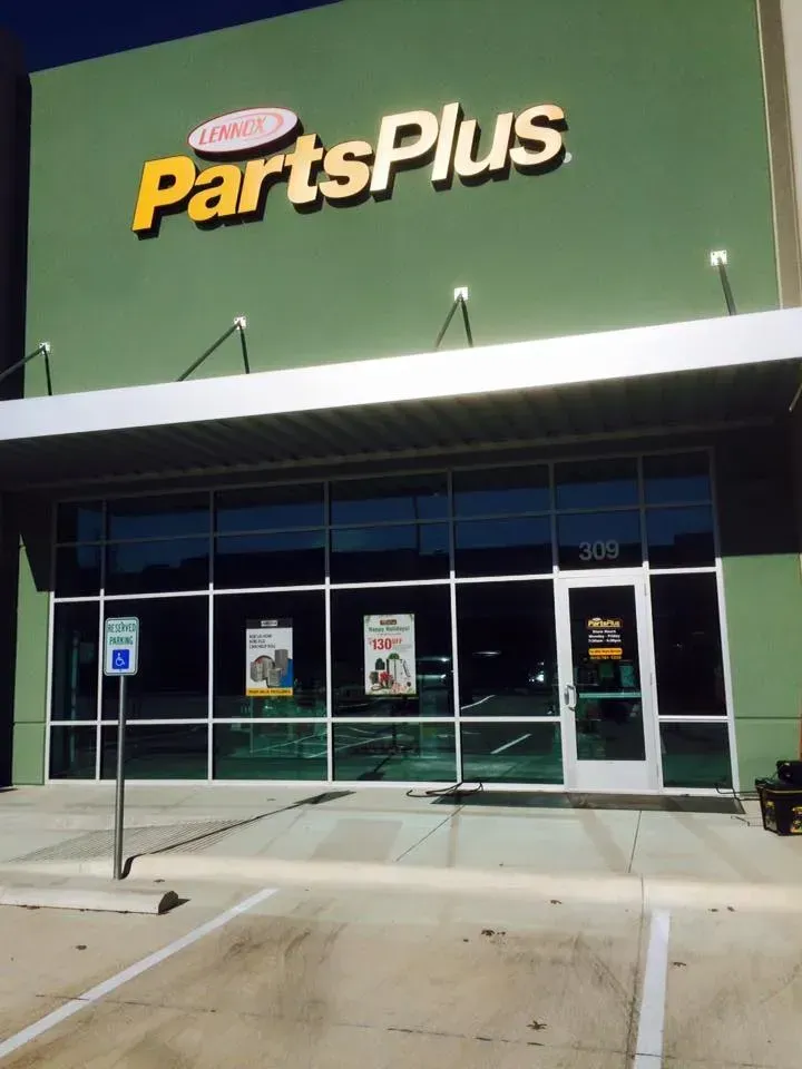 PartsPlus auto parts store exterior with sign and glass windows. Green building, parking space, and door.