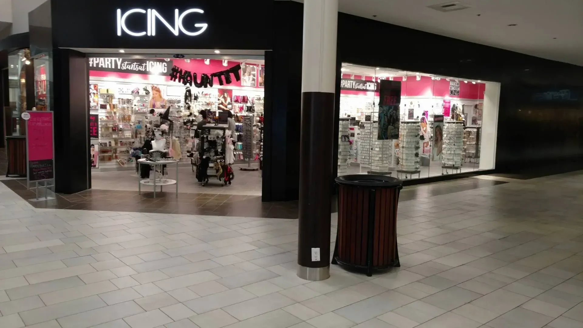 Icing store front in a mall setting; black entrance, pink interior display, various jewelry stands.