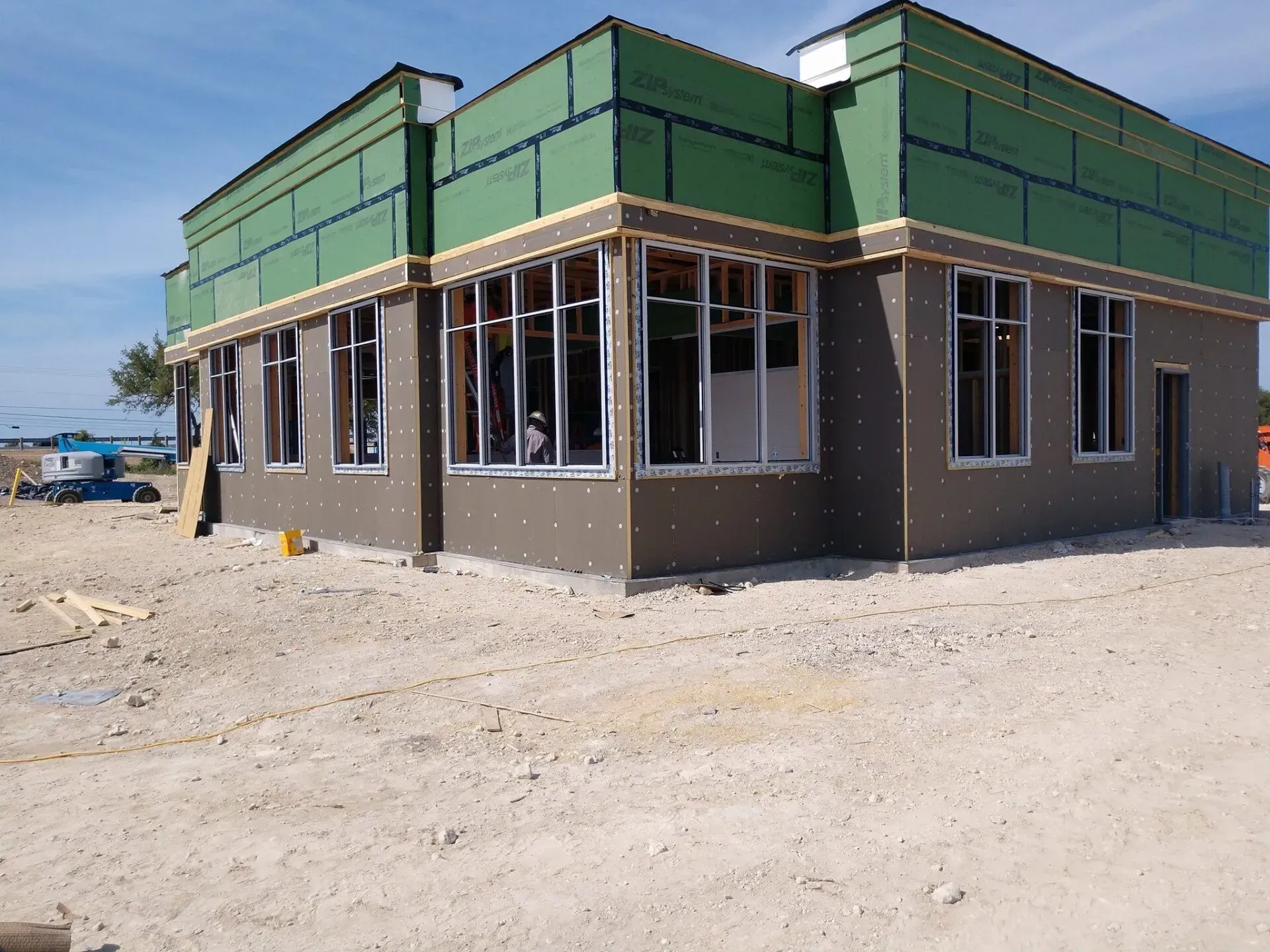 Building under construction with exterior walls, windows, and exposed wooden framing.