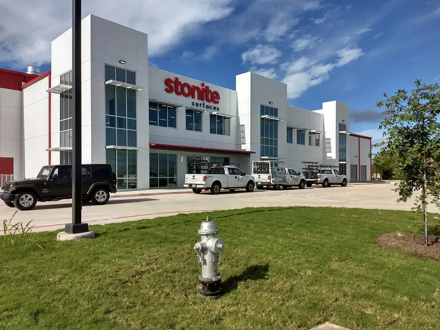Storite self-storage building with red trim, white walls, and a line of work trucks parked outside.