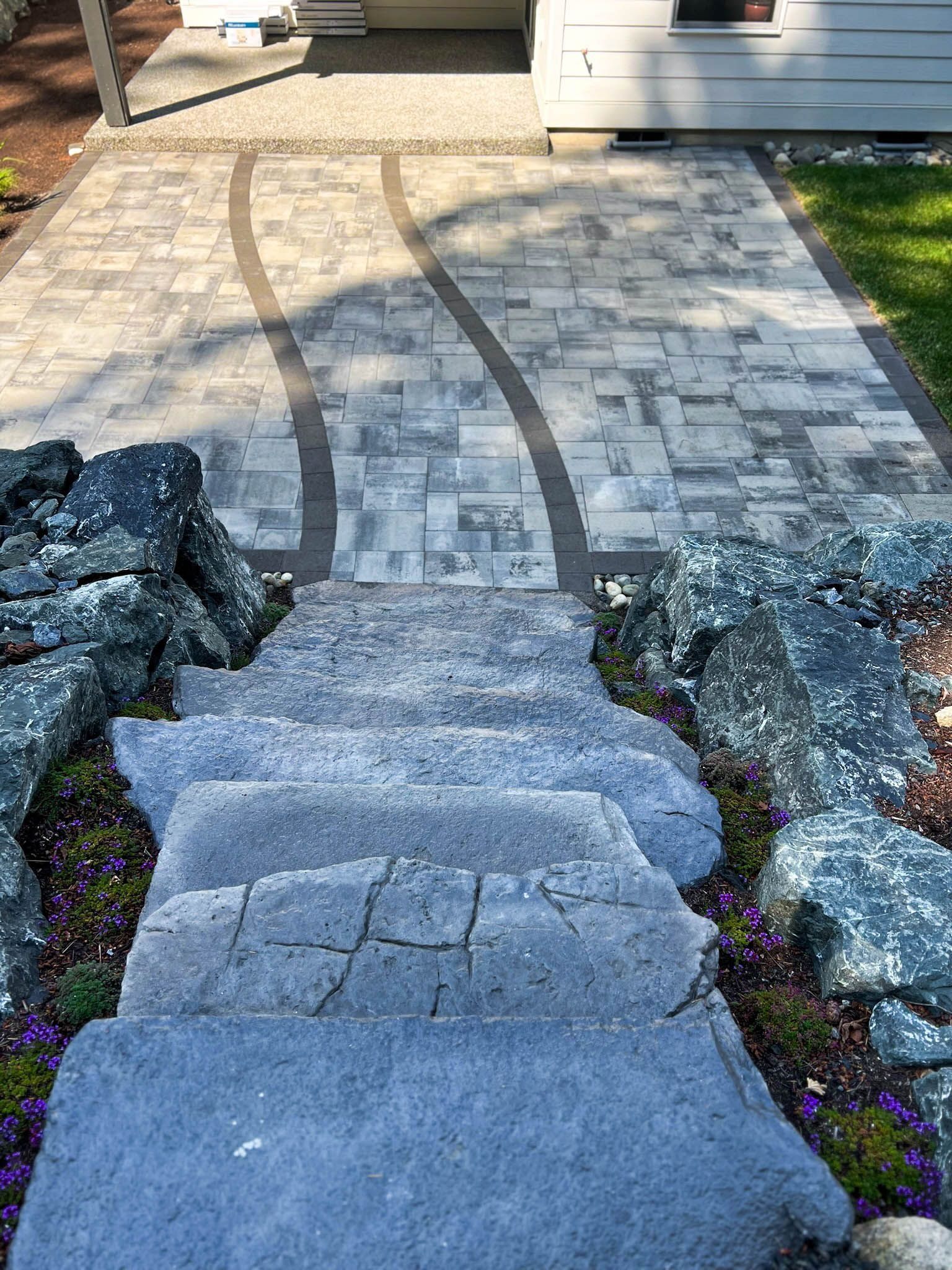 Stone steps leading to a paved path with a dark border, leading to a white building.
