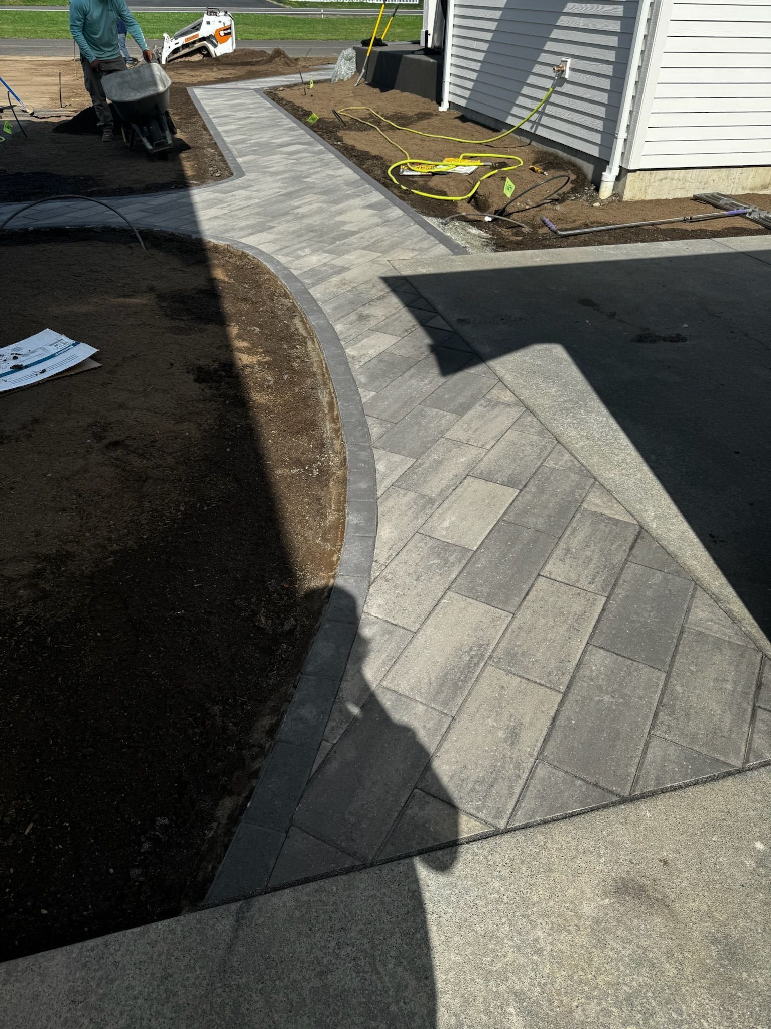 Pathway construction: Brick walkway curves into driveway with adjacent planting bed.