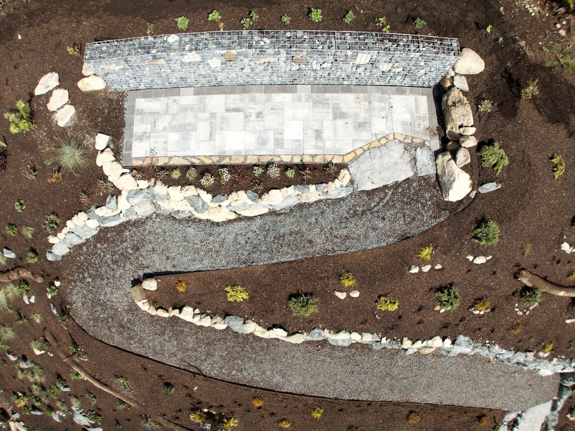 Overhead view of a landscaped patio with a stone path leading to it.