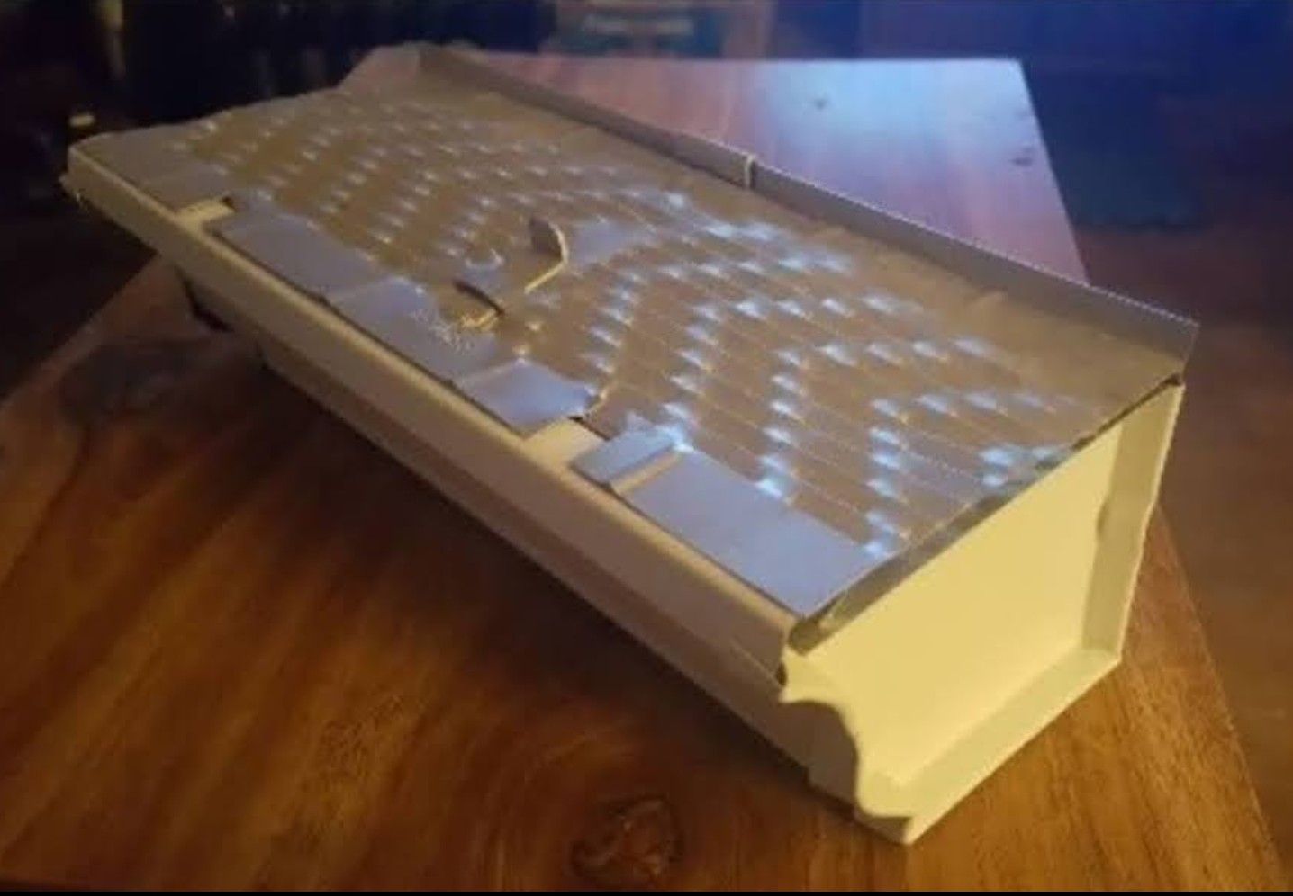 A white keyboard is sitting on a wooden table.