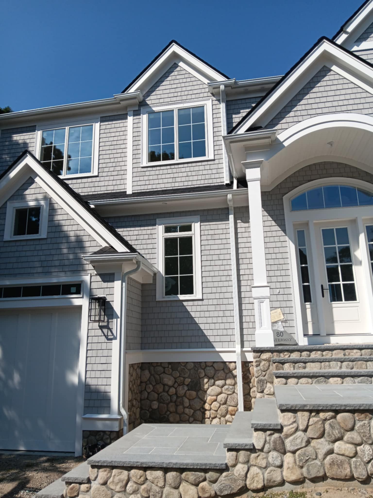 A large grey house with a white garage door.