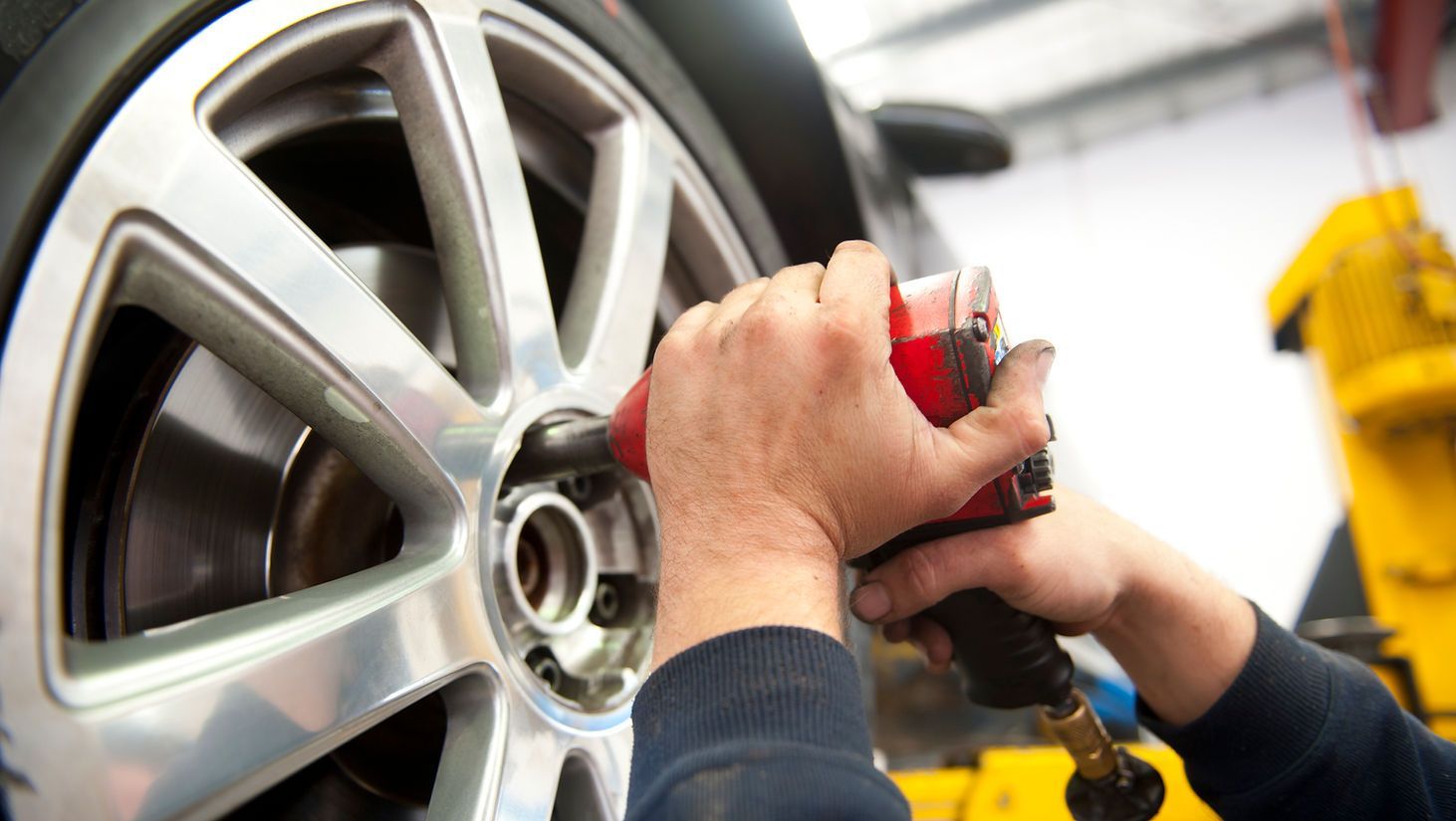 A person is working on a car wheel with a wrench.