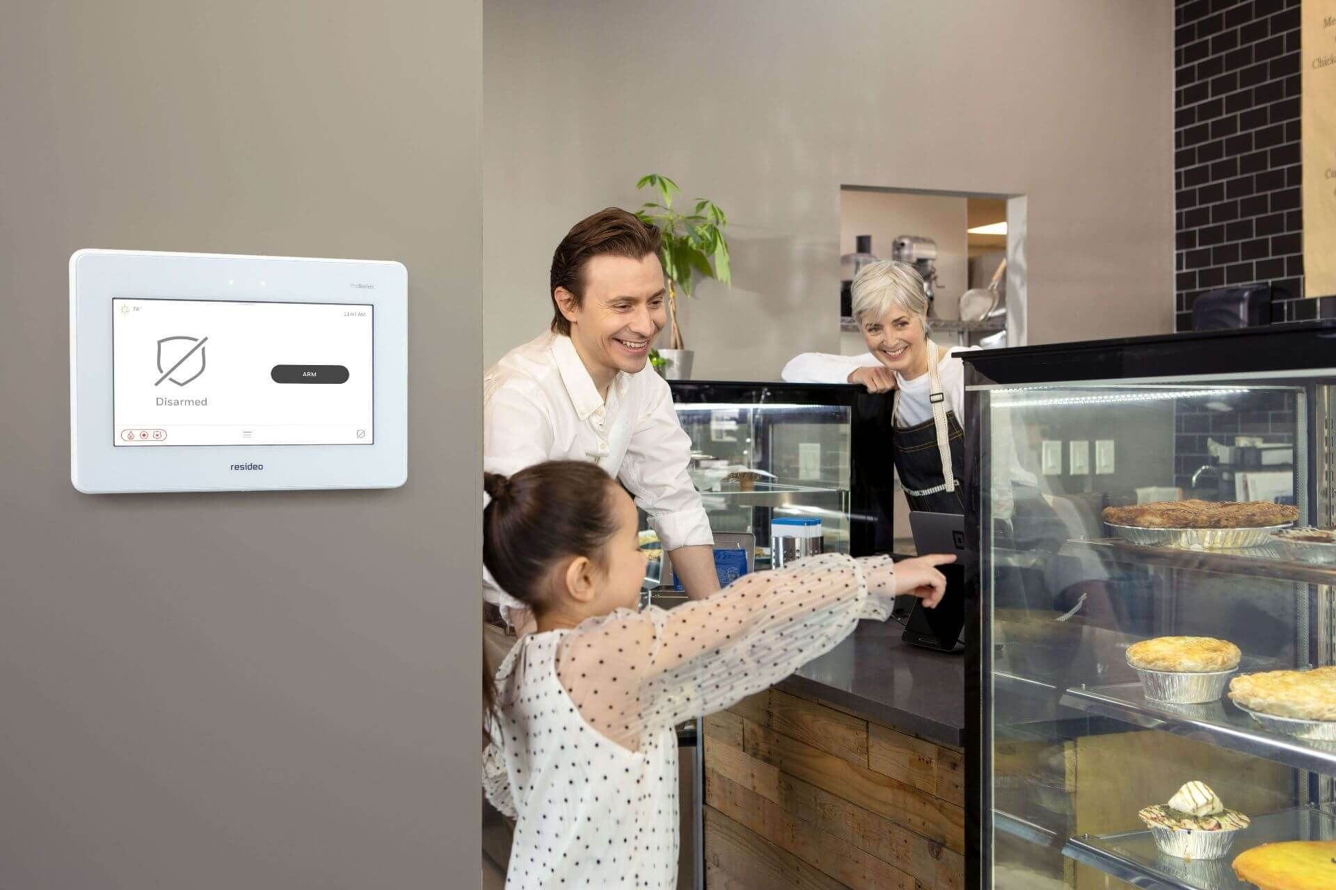 White security panel on a wall. Family in a bakery, child pointing at a display case.