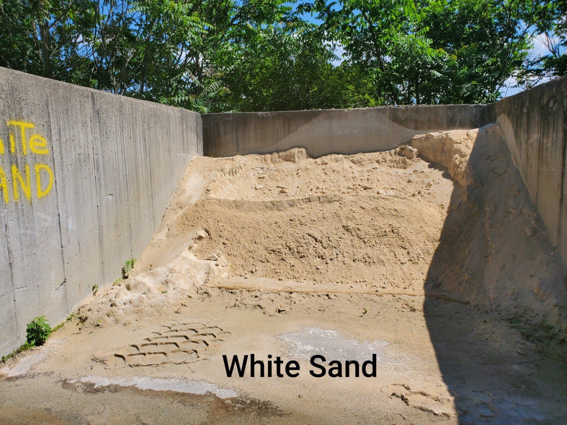 A pile of white sand is sitting next to a concrete wall.