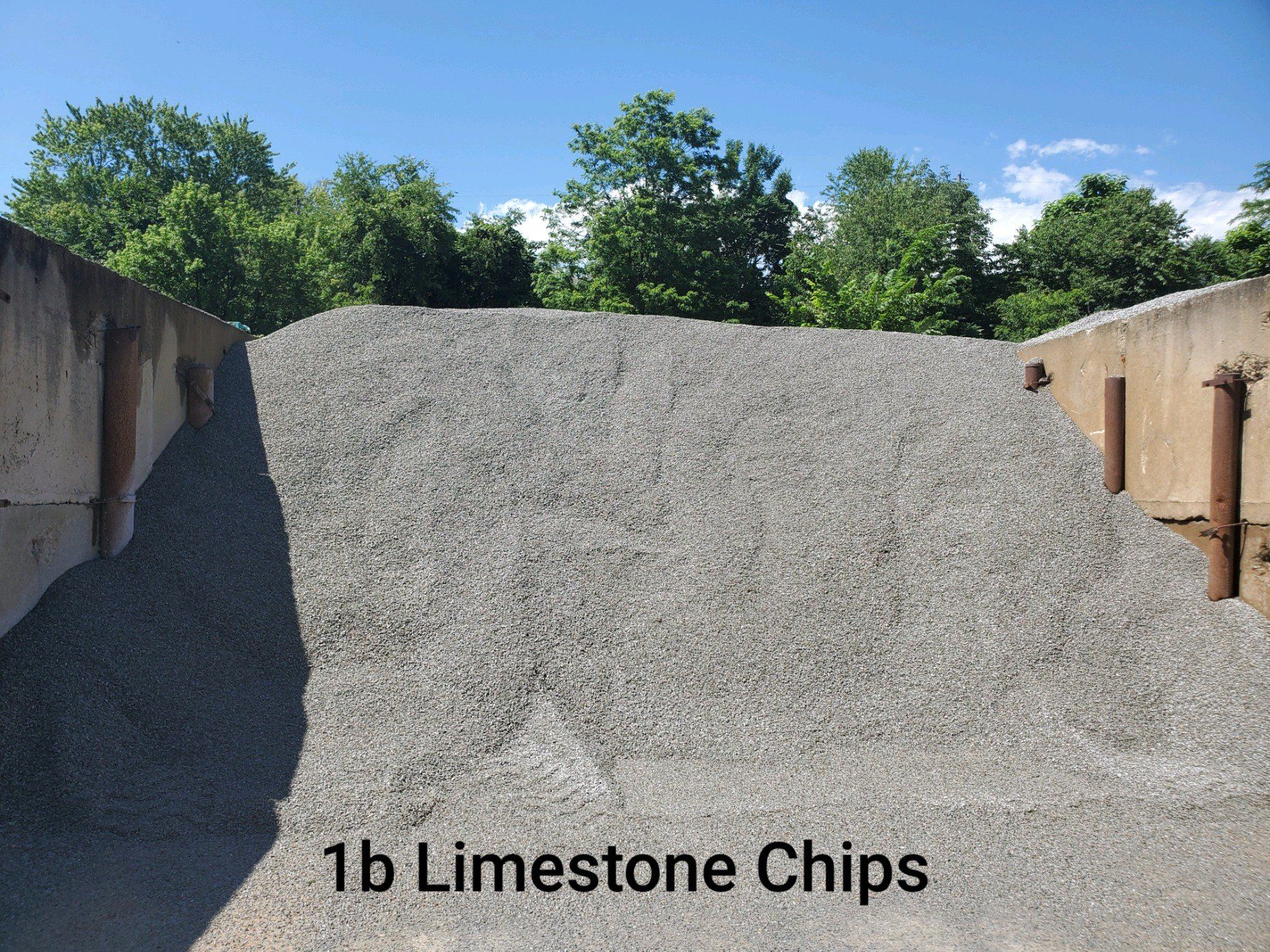 A pile of 1b limestone chips sits in front of trees