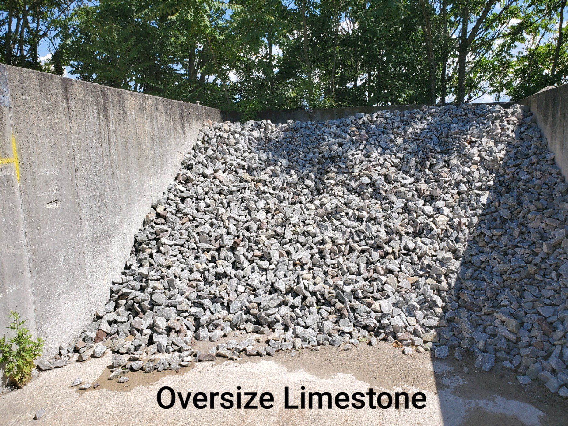 A pile of oversized limestone is sitting in front of a concrete wall