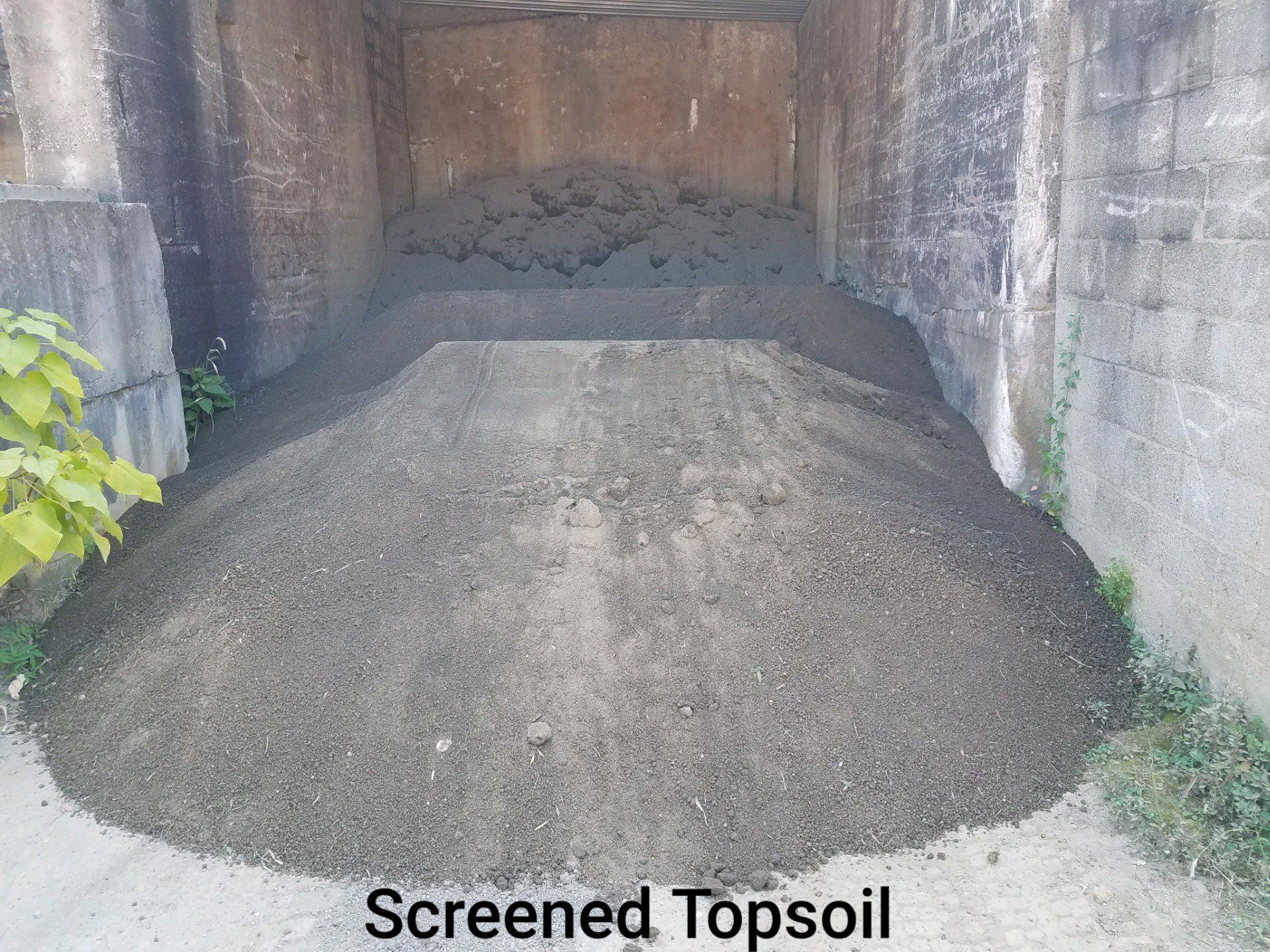 A pile of screened topsoil is sitting outside of a building