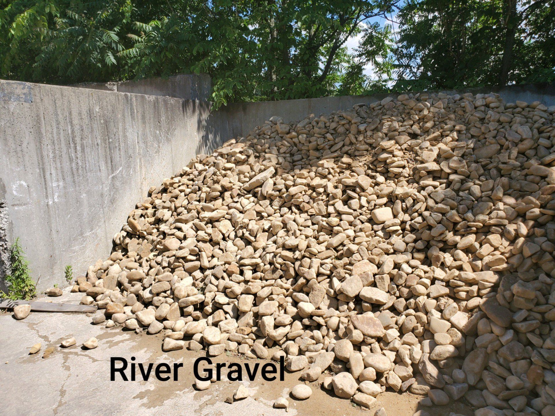 A pile of river gravel is sitting in front of a concrete wall