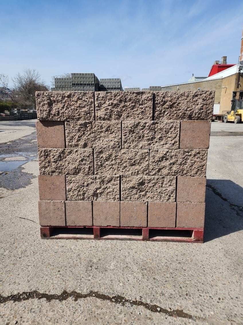 A pallet of bricks is sitting on the ground in a parking lot.