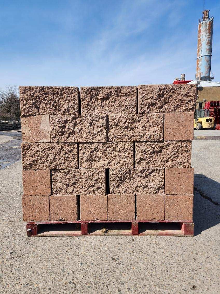 A pallet of bricks is sitting on the ground in front of a factory.