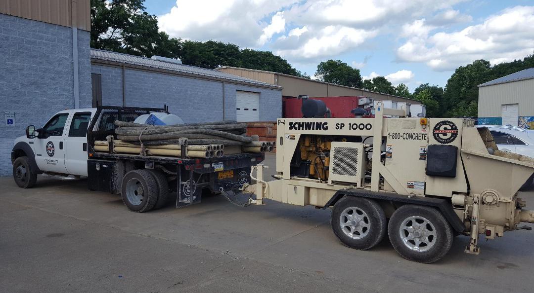 A truck with a trailer attached to it is parked in front of a building.