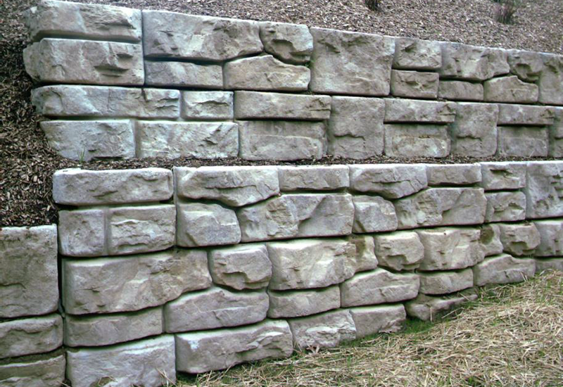 A large stone wall is sitting on top of a grass covered field
