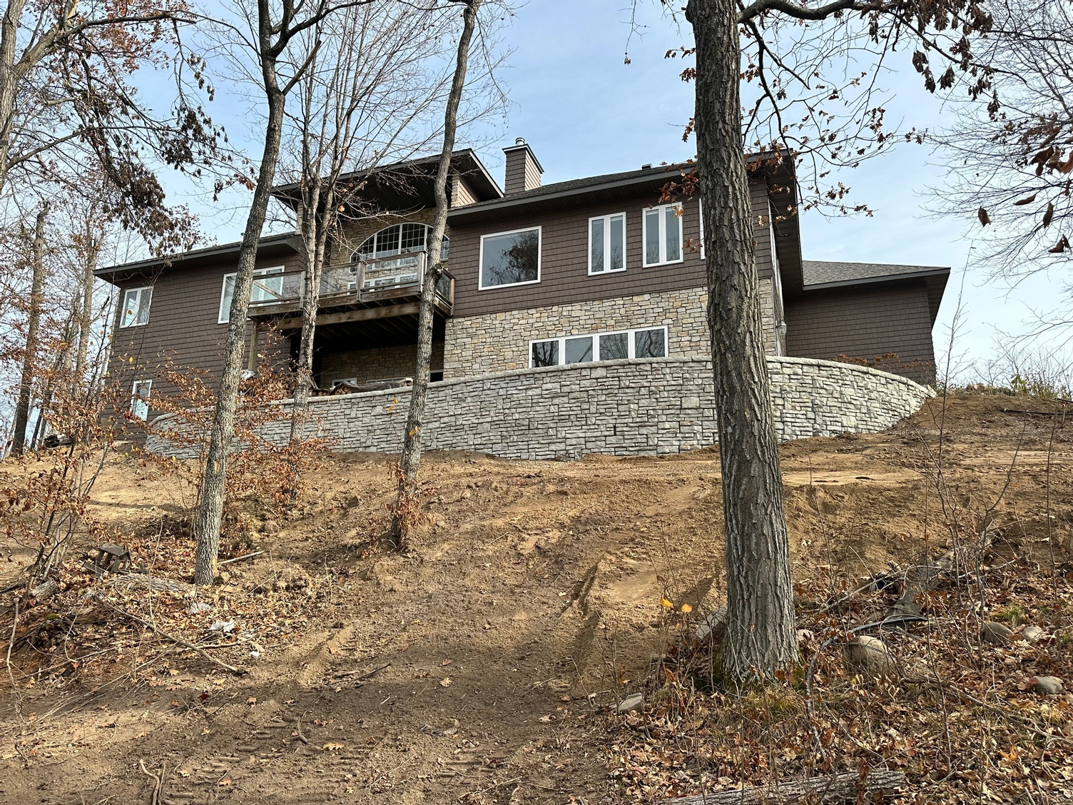 A large house is sitting on top of a hill surrounded by trees.