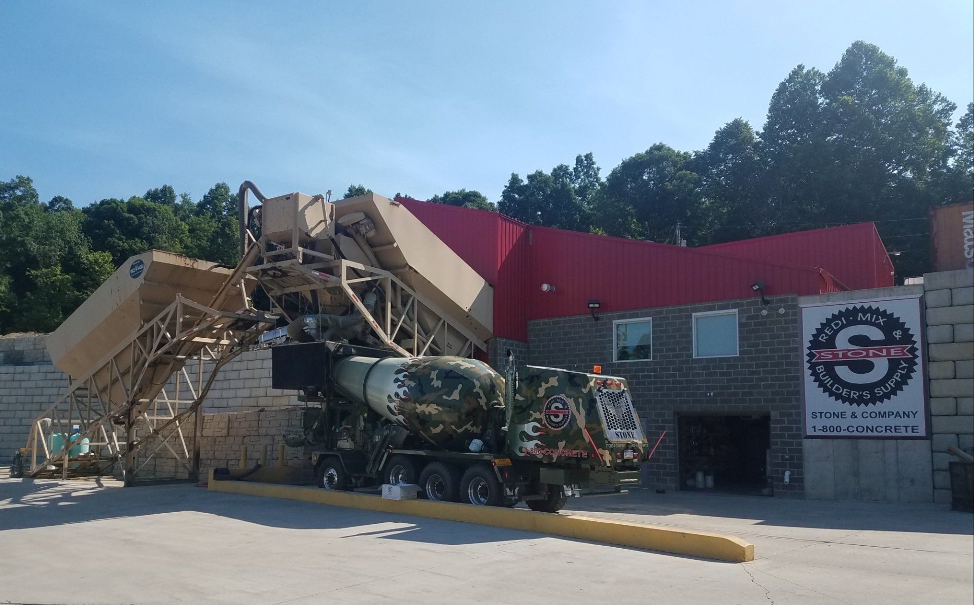 A concrete mixer truck is parked in front of a building