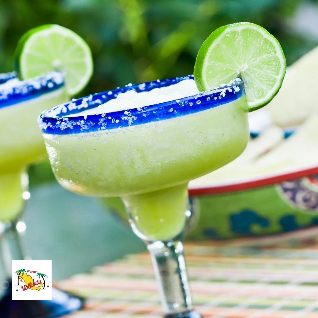 A green margarita with a blue rim and lime slices