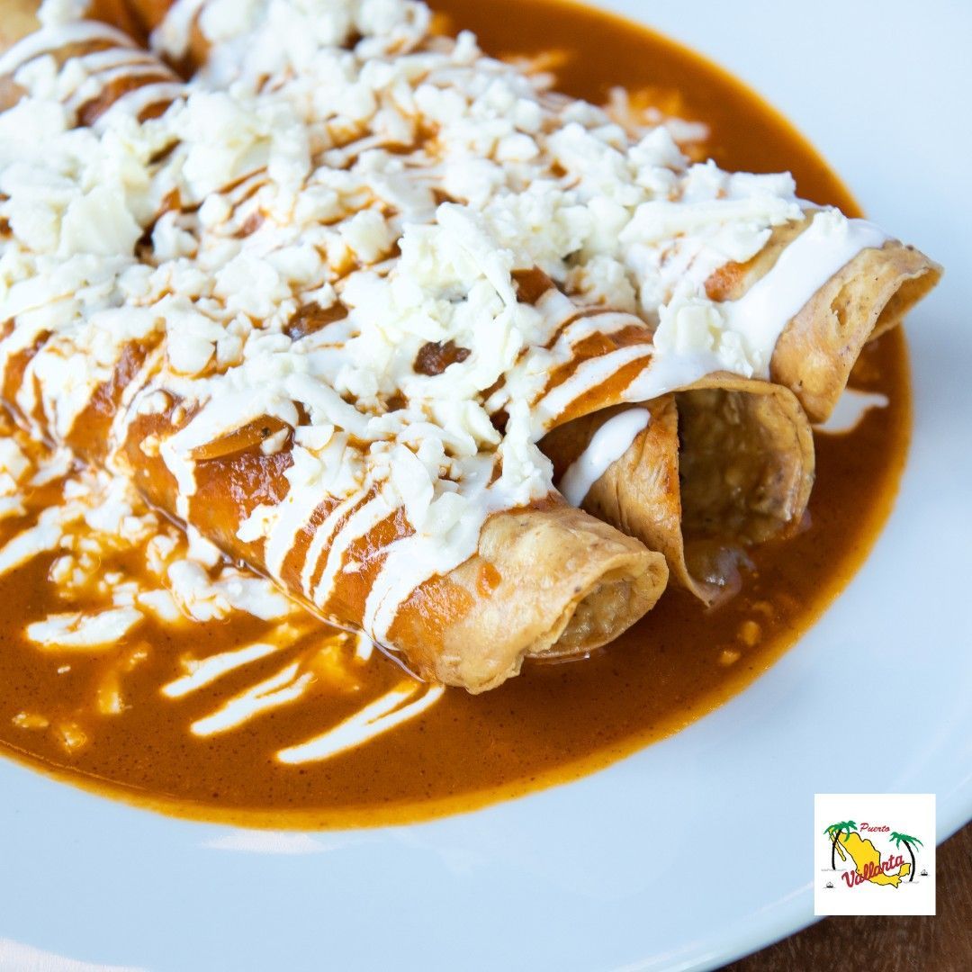 A white plate topped with enchiladas covered in sauce and cheese