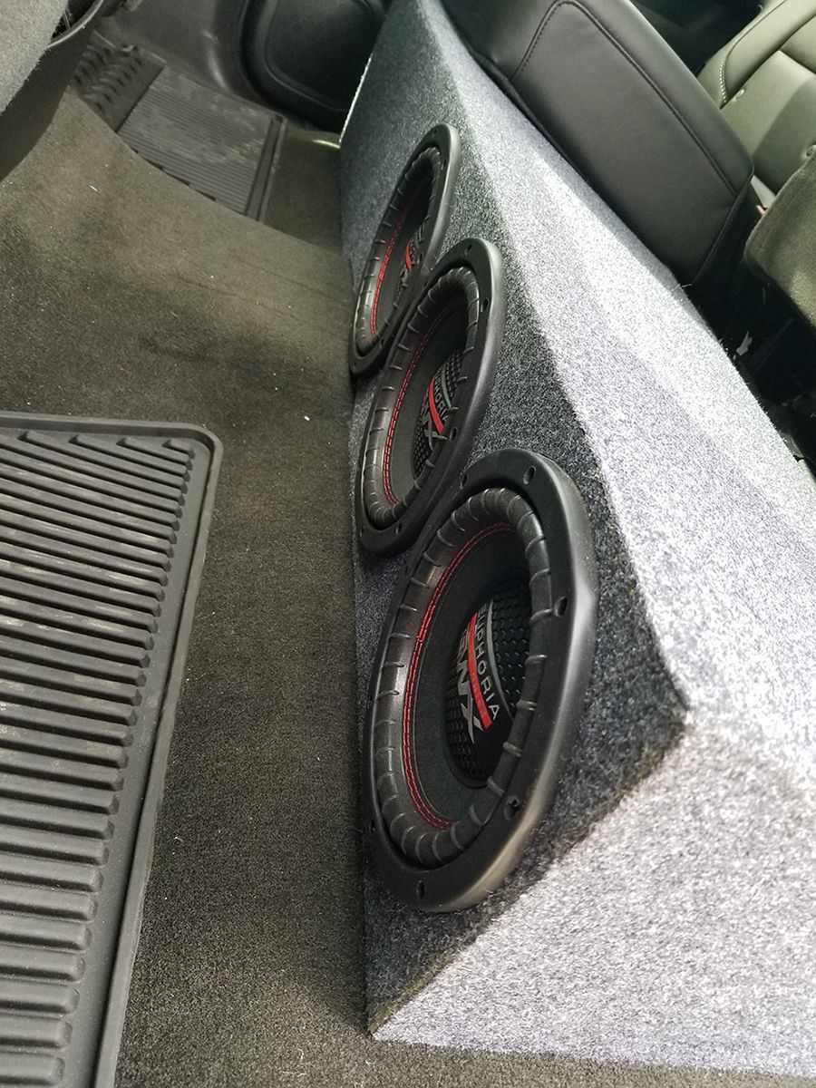Three speakers are sitting in a box in the back of a car