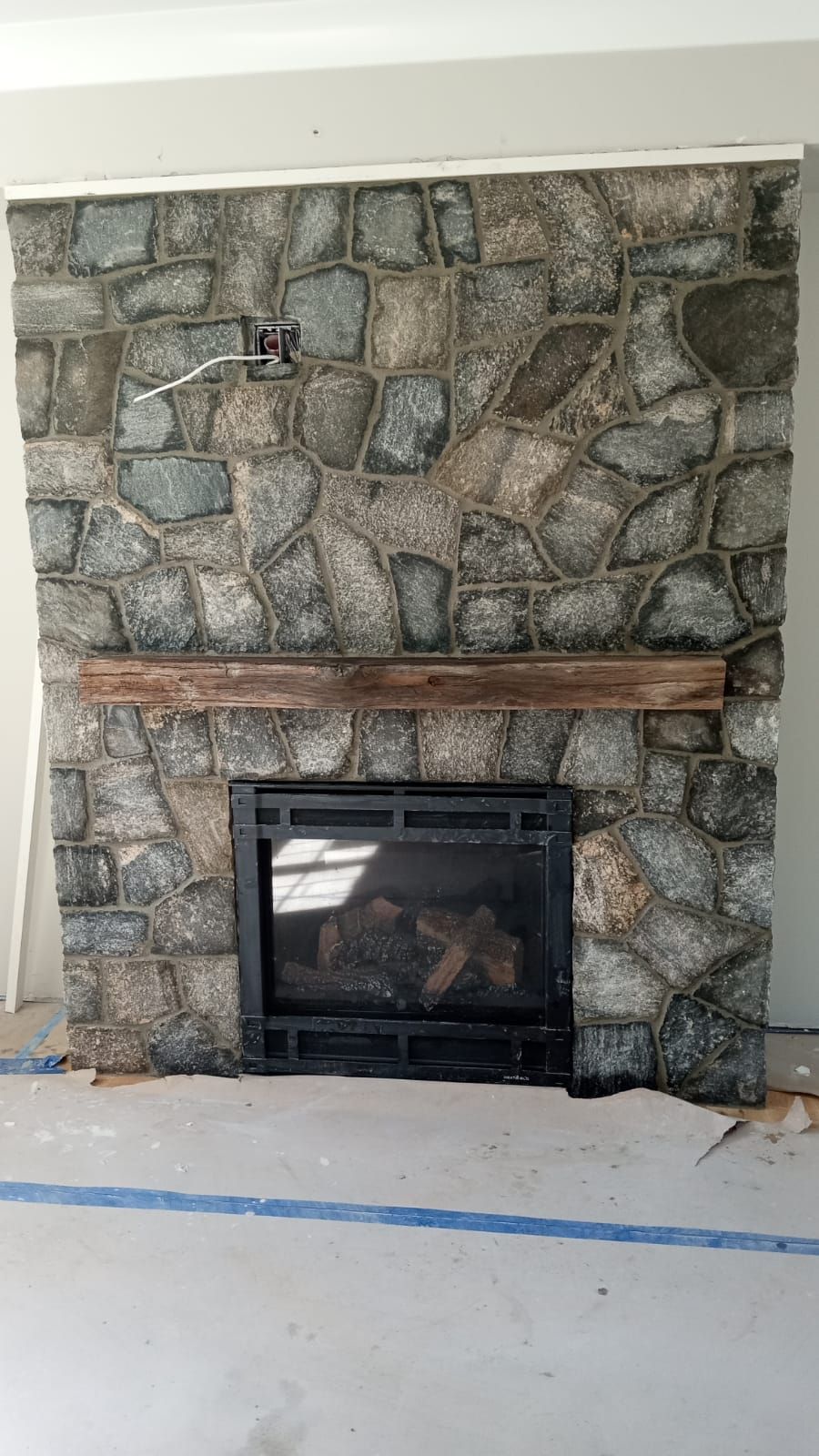 A stone fireplace with a wooden mantle in a living room.