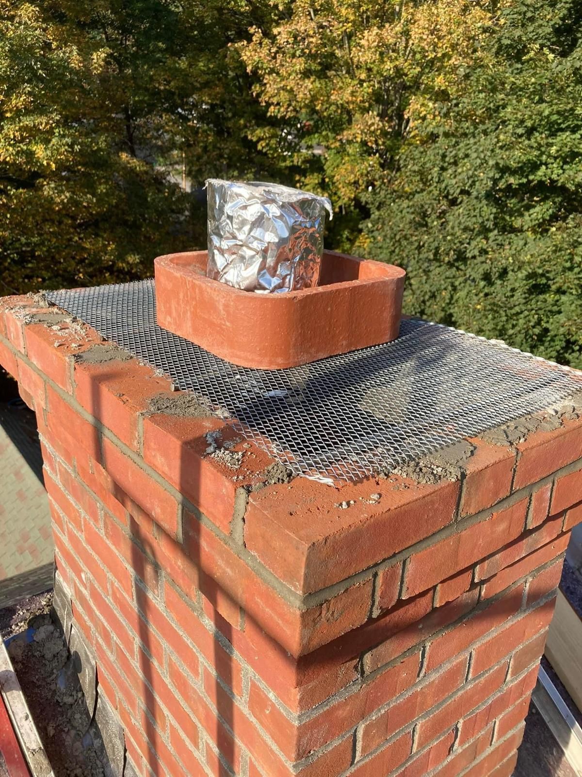 A brick chimney with a piece of tin foil on top of it.