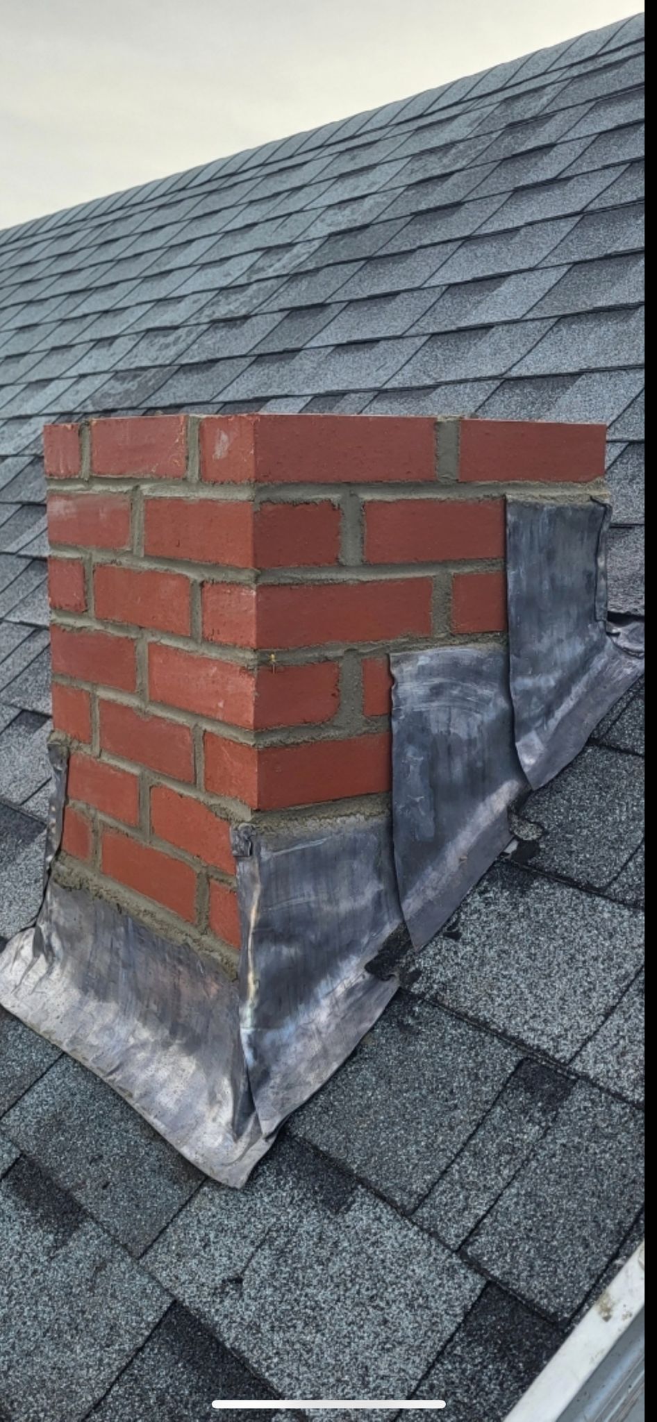 A brick chimney is sitting on top of a roof.