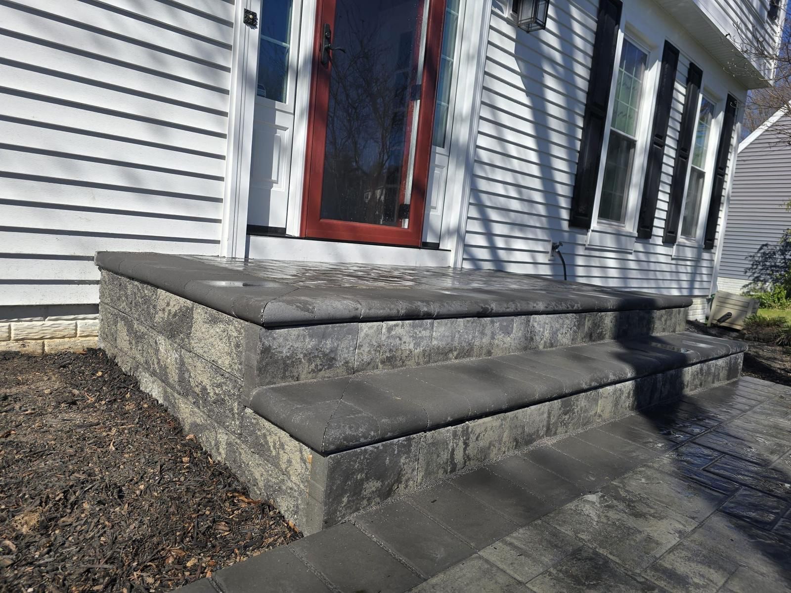 A stone porch with steps leading up to the front door of a house.