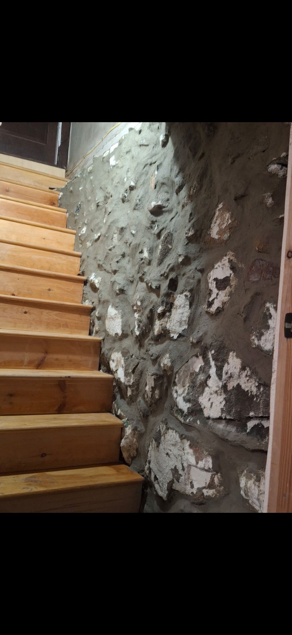 A wooden staircase leading up to a stone wall.