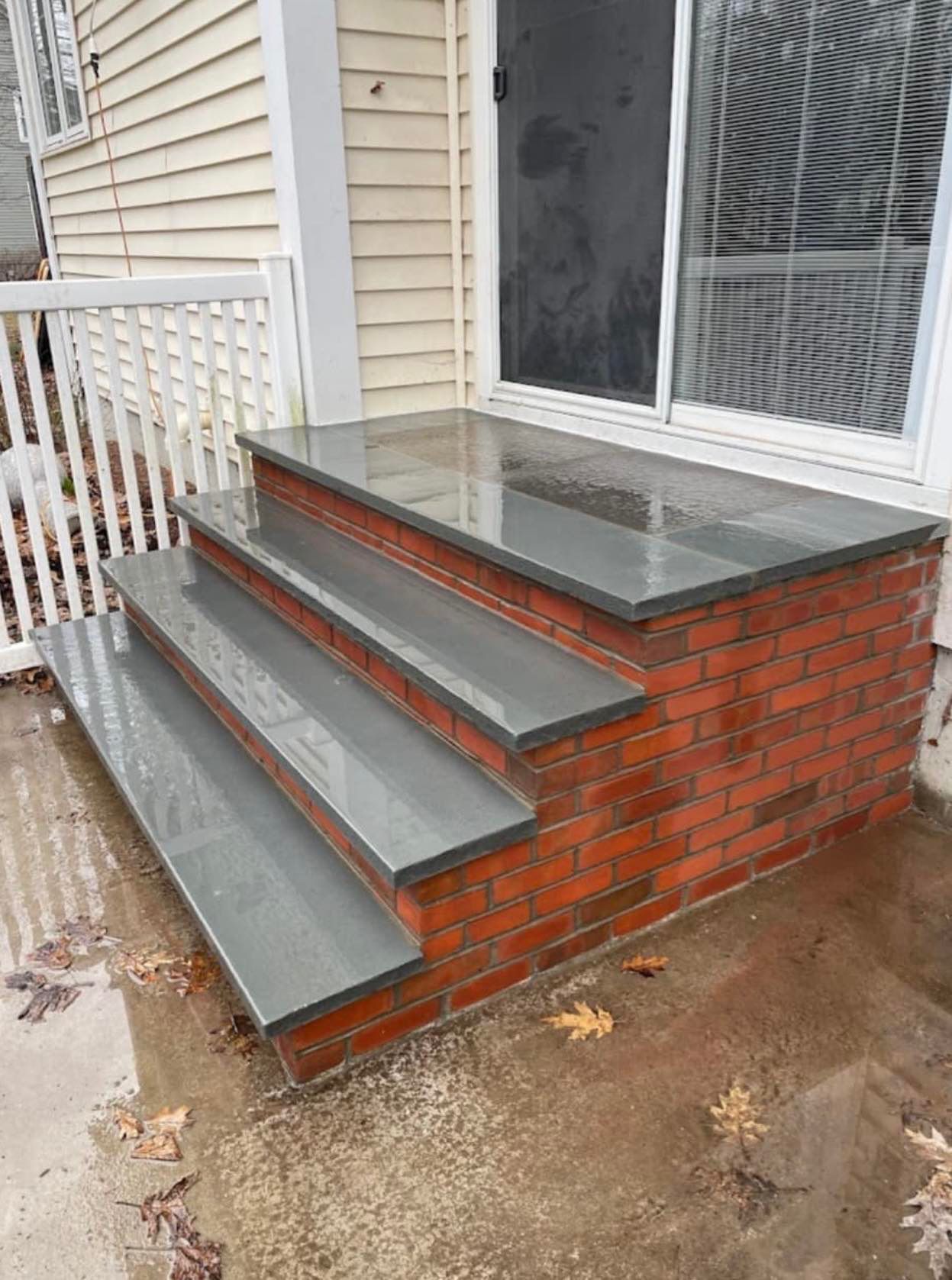 A brick porch with stairs and a sliding glass door.