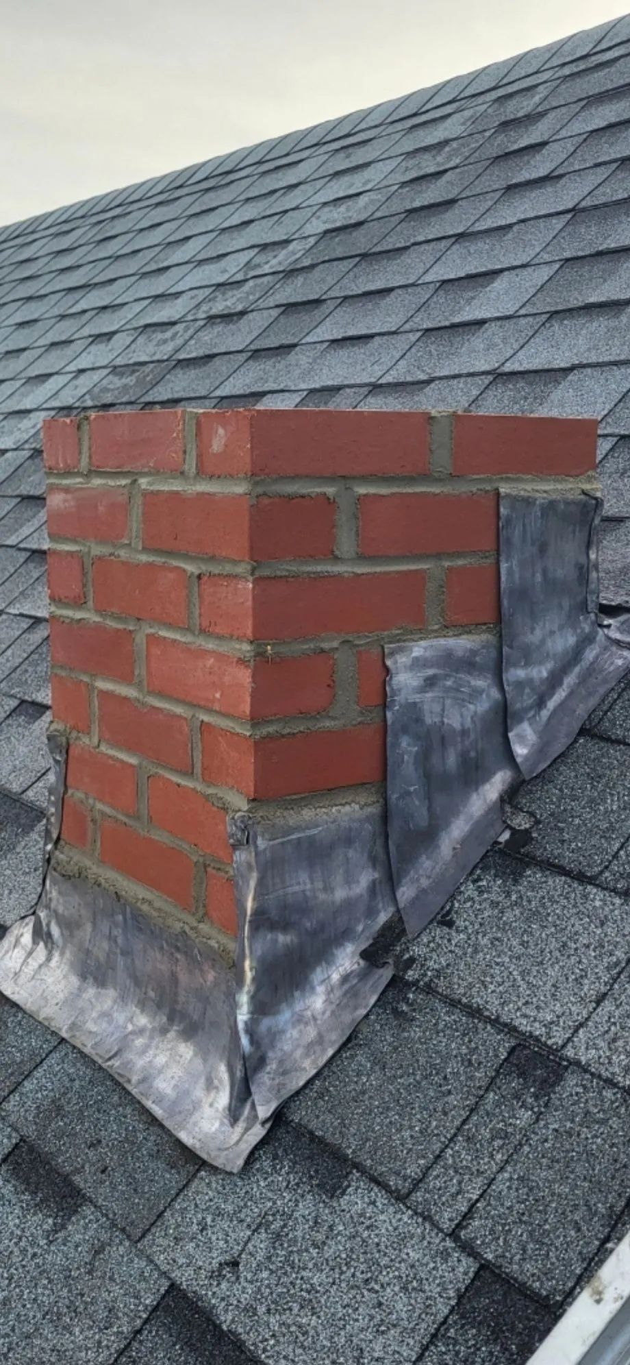 A brick chimney is sitting on top of a roof.