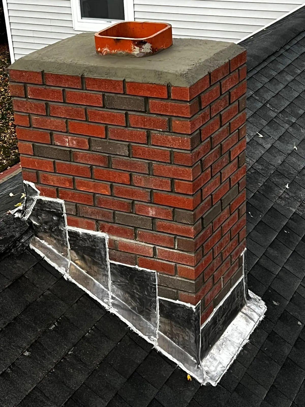 A brick chimney is sitting on top of a roof.