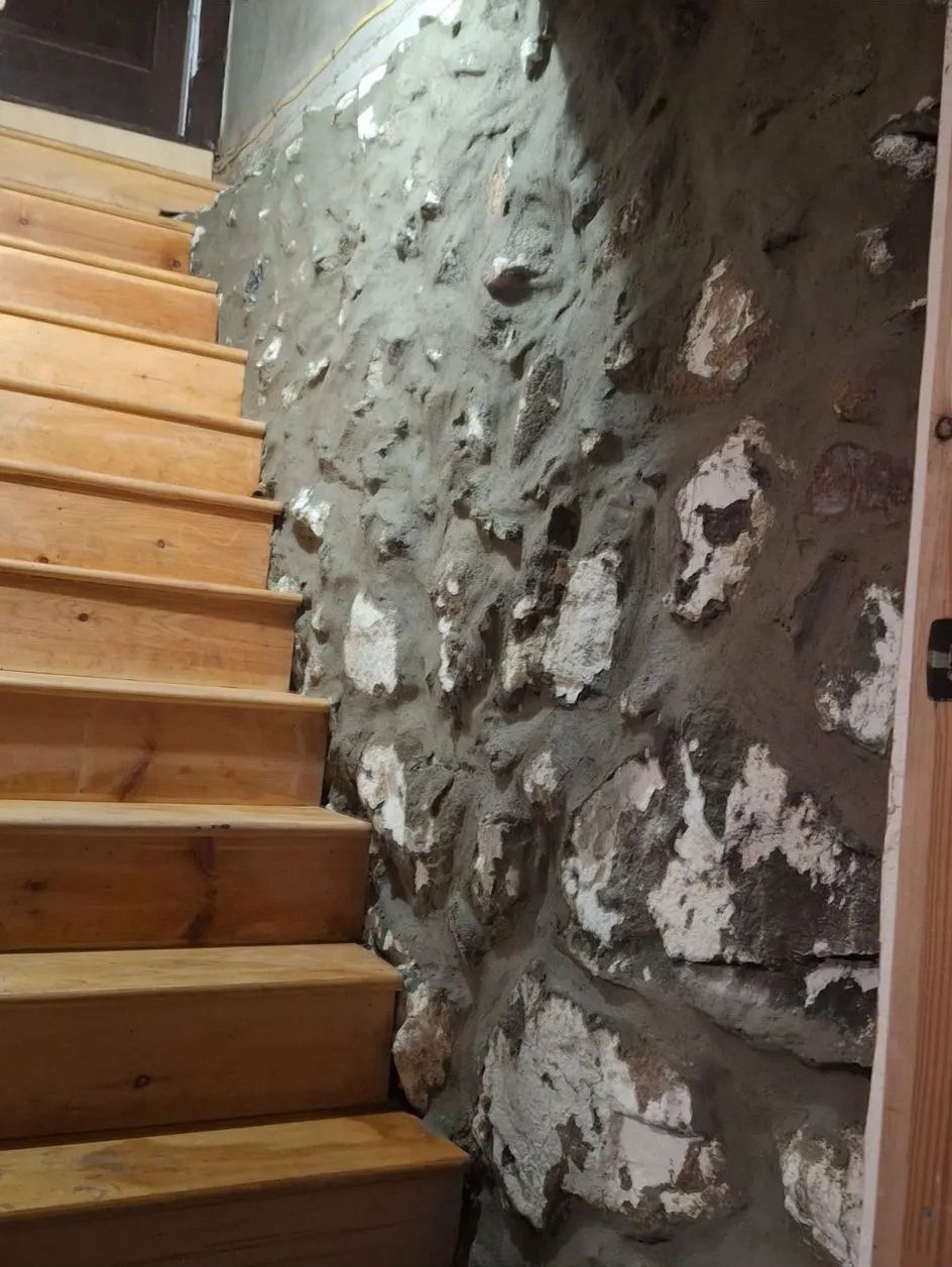 A wooden staircase leading up to a stone wall