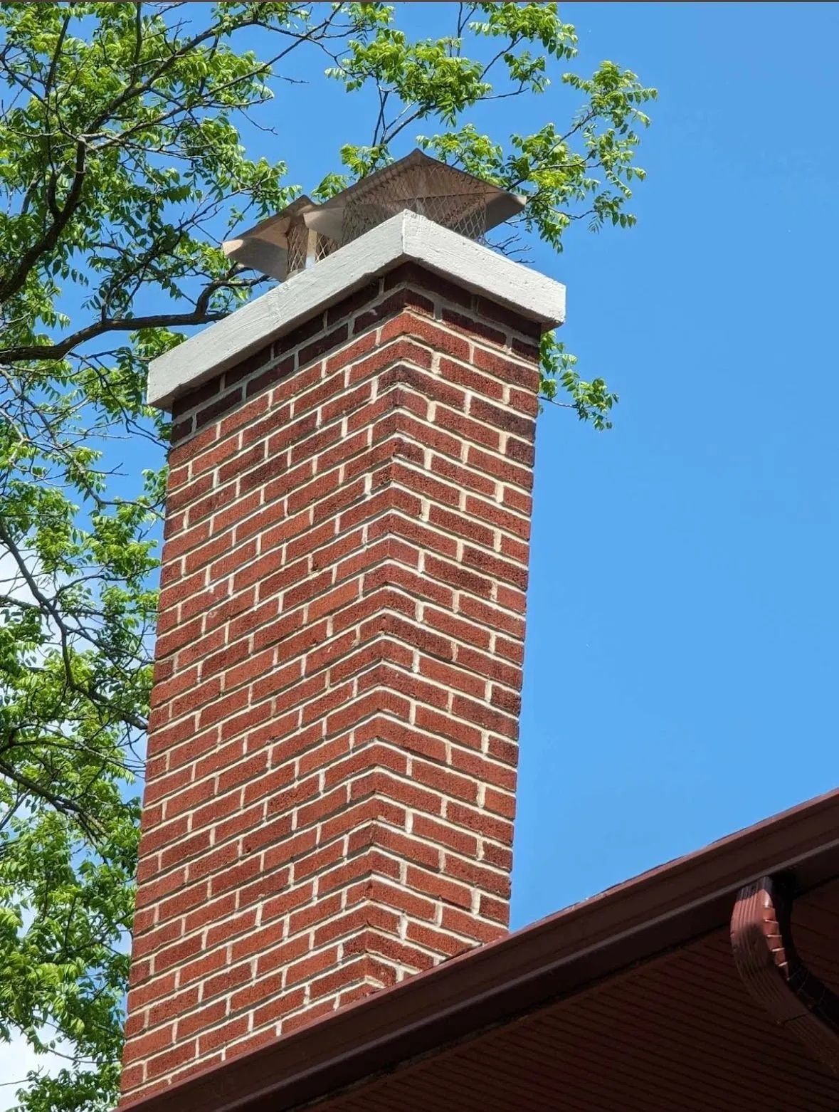 A brick chimney with a bird on top of it