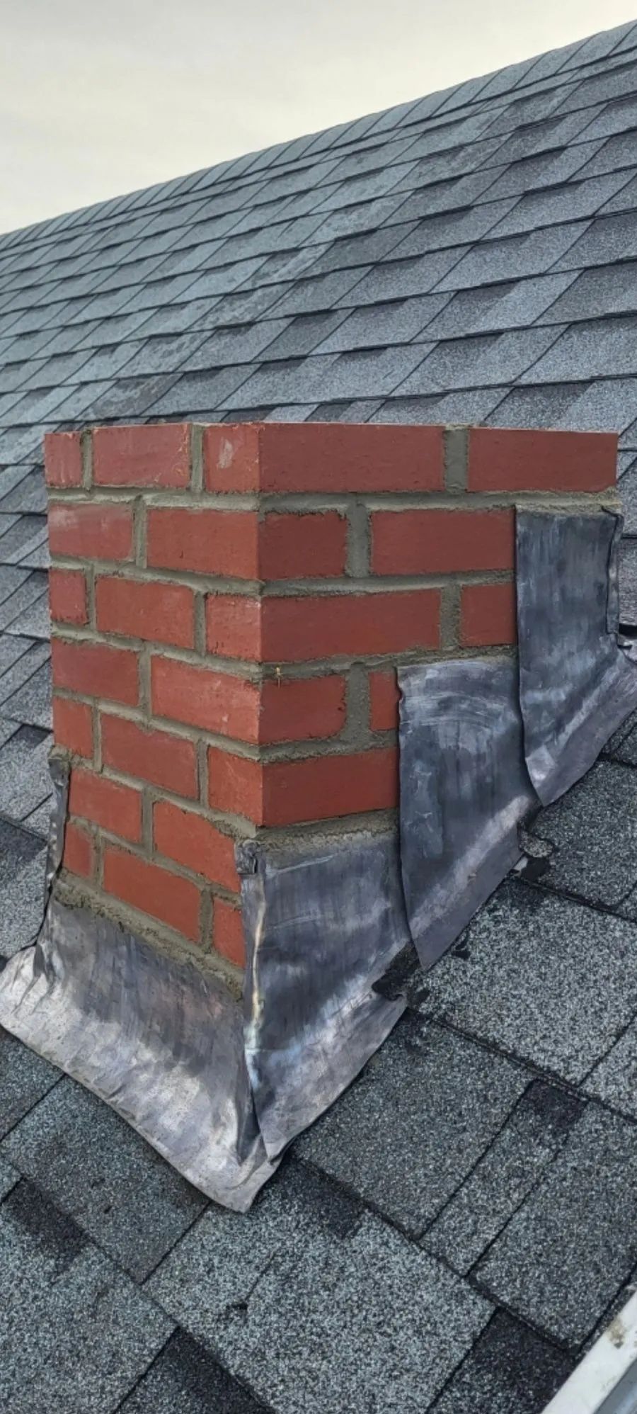 A brick chimney is sitting on top of a roof.