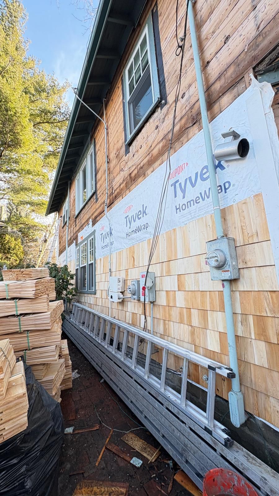 A ladder is sitting on the side of a wooden house.