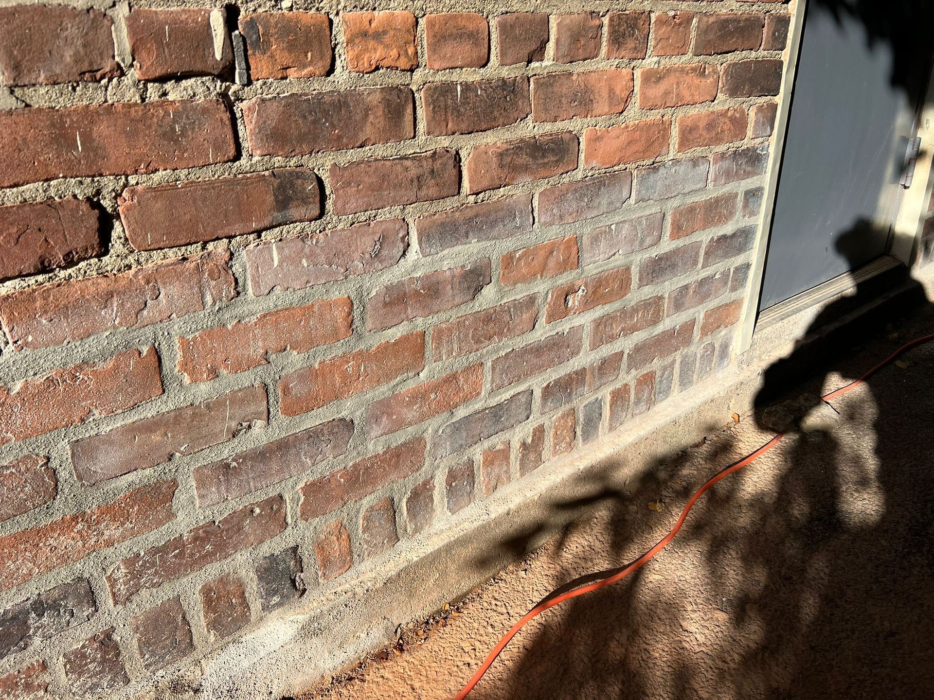 A brick wall with a red cord coming out of it.
