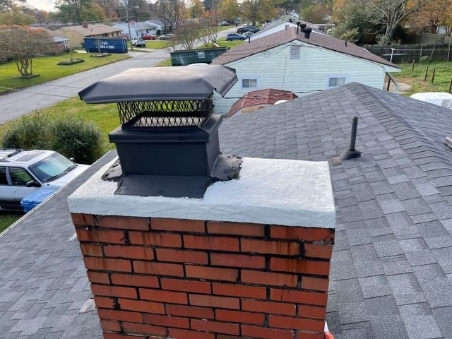 A brick chimney on top of a roof next to a house