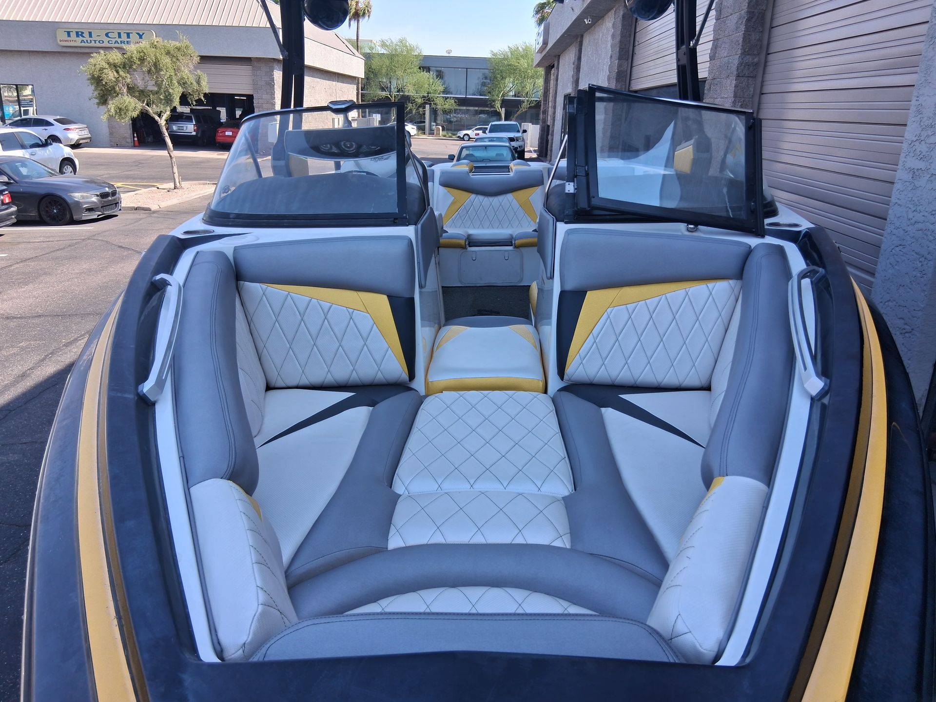 Boat interior with gray, white, and yellow seats. Two windshields and a central storage area are visible.  Exterior shot.